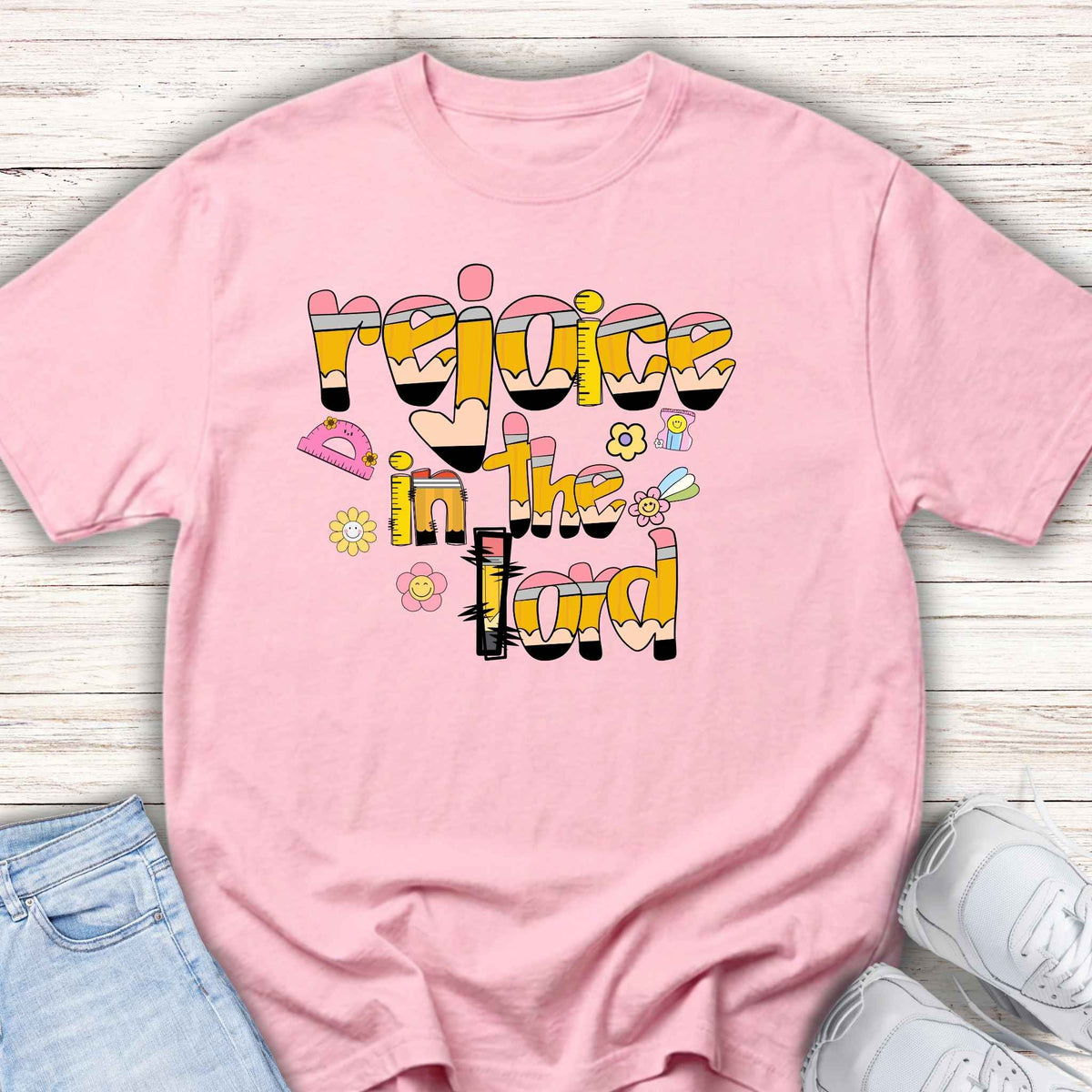 Pink t-shirt with colorful text design on a wooden surface